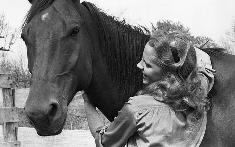 Reba with arms wrapped around horse